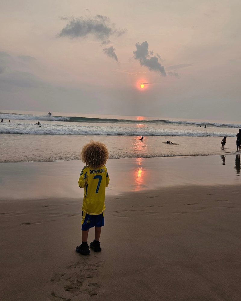 Keanu Tetteh on the beach at sunset, seen from behind