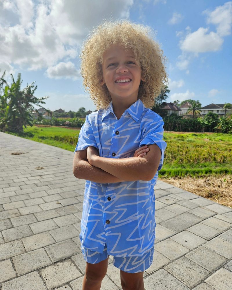 Keanu Tetteh with his arms crossed in a blue patterned set