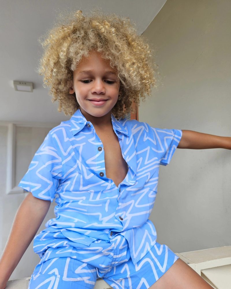 Keanu Tetteh lounging in a blue patterned shirt and shorts